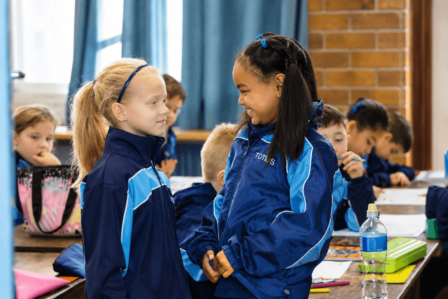 Twee leerders deel idees terwyl hul klasmaats werk