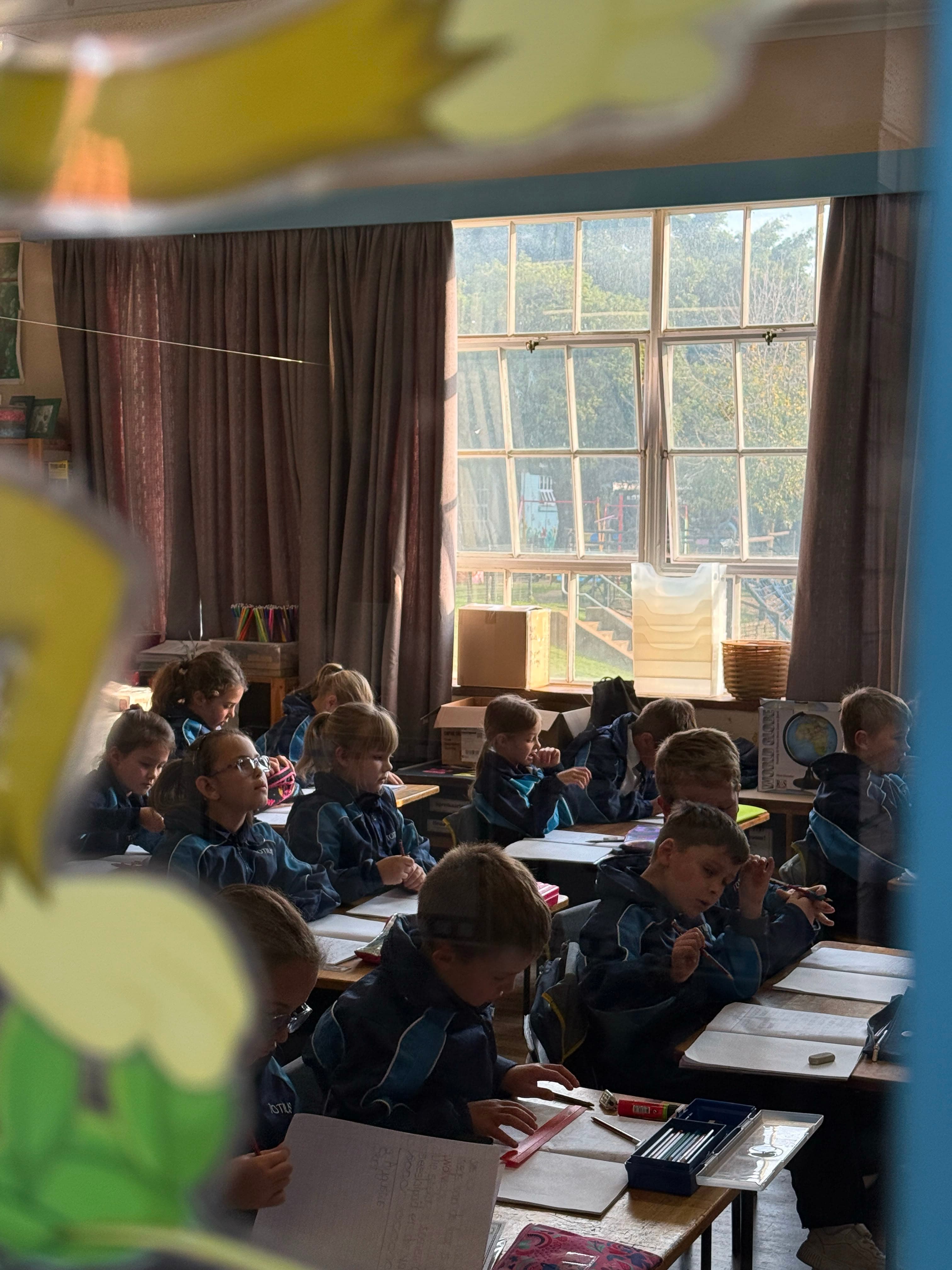 Jong leerders werk in 'n sonnige klaskamer